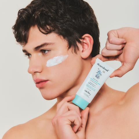 Model holding Keith Haring Tone Blur Essence Sunscreen SPF 50+ PA++++ across jawline with product applied on cheekbone