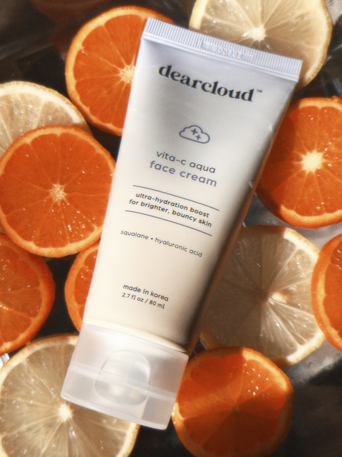 A yellow blue gradient moisturizer tube of 3.7 fl oz. Ultra-hydrating moisturizer boost for brighter, bouncy skin. Shown laying on top of circular slices of orange and lemon.