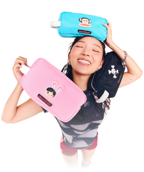 Model holding three Paul Frank Cosmetics Bags: Julius Teal, Bunny Girl Pink, and Skurvy Black.