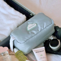 A baby blue makeup bag that has a blue cloud and the "dearcloud" logo in the center of the bag. The bag is in a suitcase surrounded by a white towel, other dearcloud products, and  camera. 
