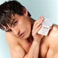 Male model with textured wet hair holding white square rounded bottle with light blue cloud cap.