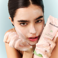 Model holding facial cleanser with bubble foam on hands and face