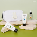 Rectangular puffy white cosmetics bag with a Miffy bunny patch on it next to travel sized bottles of cream, cleanser, and serum.