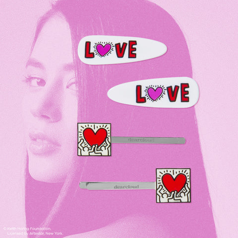 A close-up of three hair clips featuring the iconic Keith Haring heart design.