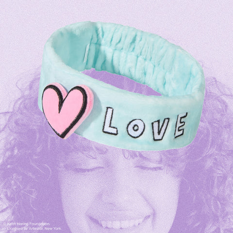 A soft blue headband with the word "LOVE" and a heart design, inspired by Keith Haring.